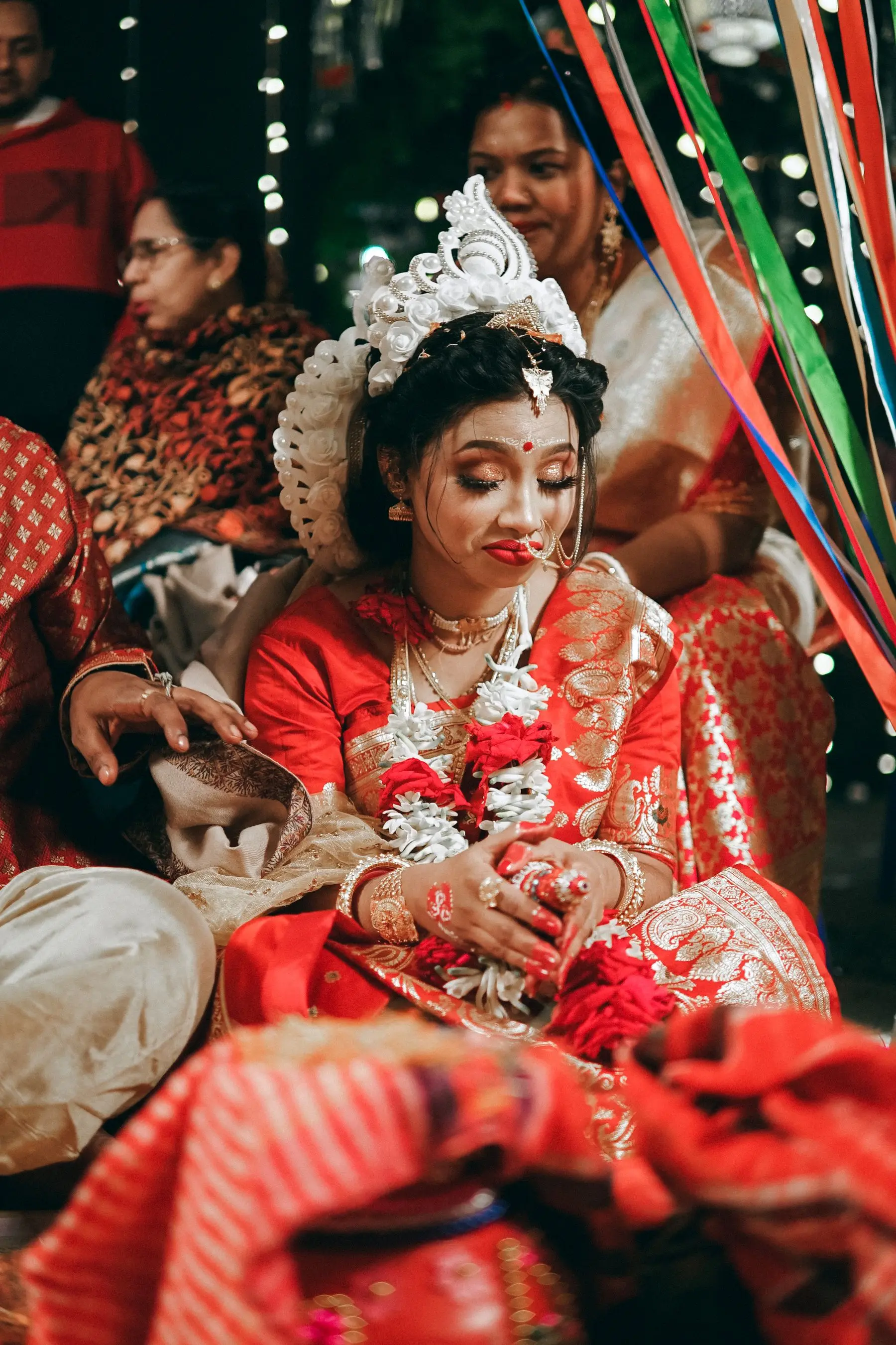 Indian bride and groom in traditional Bengali wedding dress sharing a ceremony moment.